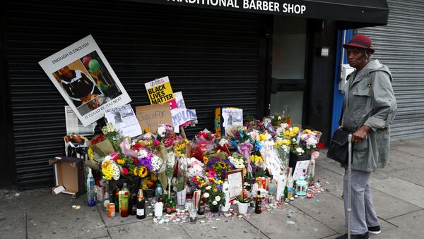 A woman looks at floral tributes laid after the death of Rashan Charles outside a shop in east London - Sputnik International