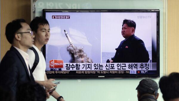 South Korean men pass by a TV news program showing images published in North Korea's Rodong Sinmun newspaper of North Korea's ballistic missile believed to have been launched from underwater and North Korean leader Kim Jong-un, at Seoul Railway station in Seoul, South Korea, Saturday, May 9, 2015 - Sputnik International