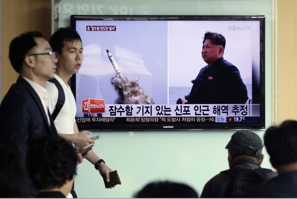 South Korean men pass by a TV news program showing images published in North Korea's Rodong Sinmun newspaper of North Korea's ballistic missile believed to have been launched from underwater and North Korean leader Kim Jong-un, at Seoul Railway station in Seoul, South Korea, Saturday, May 9, 2015 - Sputnik International