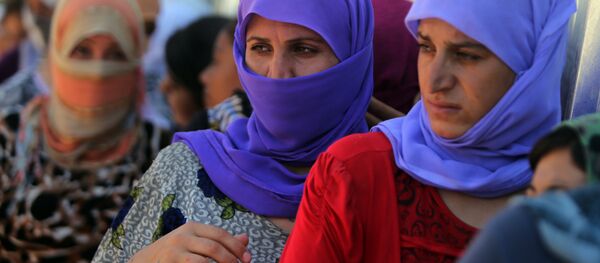 Yazidi Iraqi women queue in order to get food at the Bajid Kandala camp near the Tigris River, in Kurdistan's western Dohuk province, where they took refuge after fleeing advances by Islamic State jihadists in Iraq on August 13, 2014. (File) - Sputnik International