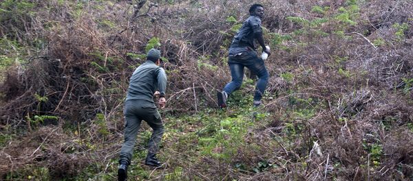 A member of the Moroccan authorities runs after a migrant on February 18, 2017 after he forced his way through a fence between Morocco and the tiny Spanish enclave of Ceuta - Sputnik International
