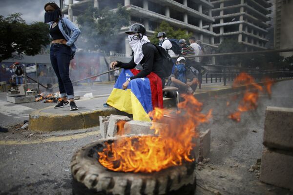 Masked anti-government demonstrators stend to a burning barricade during a protest against the installation of a constitutional assembly in Caracas, Venezuela, Friday, Aug. 4, 2017 Masked anti-government demonstrators stend to a burning barricade during a protest against the installation of a constitutional assembly in Caracas, Venezuela, Friday, Aug. 4, 2017 - Sputnik International