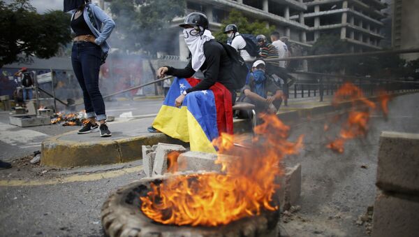 Masked anti-government demonstrators stend to a burning barricade during a protest against the installation of a constitutional assembly in Caracas, Venezuela, Friday, Aug. 4, 2017 - Sputnik International