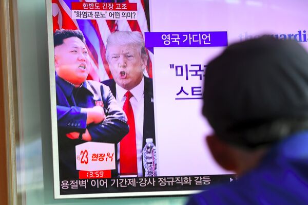 A man watches a television news programme showing US President Donald Trump (C) and North Korean leader Kim Jong-Un (L) at a railway station in Seoul on August 9, 2017 - Sputnik International