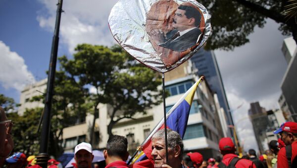 A government supporter holds a heart-shaped placard decorated with an image of Venezuela's Nicolas Maduro during a rally in support of the Constitutional Assembly outside of the National Assembly building in Caracas, Venezuela, Monday, Aug. 7, 2017. - Sputnik International