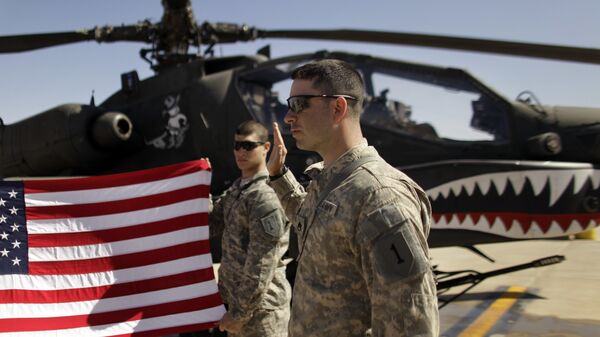 In this March 16, 2011, file photo Army Staff Sgt. Christopher Seeman, right, of Kalispell, Mont., takes the oath of re-enlistment as Spc. Brian Martinez, center, of Aurora, Ill., holds up a American flag in front of an Apache helicopter during a ceremony at Camp Taji, north of Baghdad, Iraq. - Sputnik International