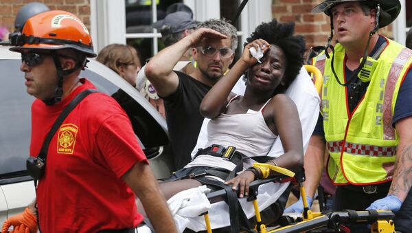 Rescue personnel help an injured woman after a car ran into a large group of protesters after an white nationalist rally in Charlottesville, Va., Saturday, Aug. 12, 2017. - Sputnik International