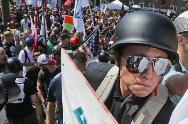 A white nationalist demonstrator with a helmet and shield walks into Lee Park in Charlottesville, Va., Saturday, Aug. 12, 2017. Hundreds of people chanted, threw punches, hurled water bottles and unleashed chemical sprays on each other Saturday after violence erupted at a white nationalist rally in Virginia. A white nationalist demonstrator with a helmet and shield walks into Lee Park in Charlottesville, Va., Saturday, Aug. 12, 2017. Hundreds of people chanted, threw punches, hurled water bottles and unleashed chemical sprays on each other Saturday after violence erupted at a white nationalist rally in Virginia. - Sputnik International