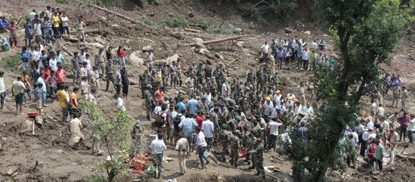 People watch army soldiers and rescue workers recover bodies of landslide victims even as they try to pull out two buses that were covered in mud after a landslide triggered by heavy monsoon rain in Urla village, Himachal Pradesh state, India - Sputnik International