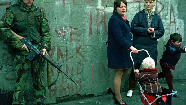 Women and children stand near an armed British military soldier patrols a street in Belfast, Northern Ireland, Feb. 1972. British paratroopers shot 13 demonstrators during a civil rights march on Jan. 30, known as Bloody Sunday. - Sputnik International
