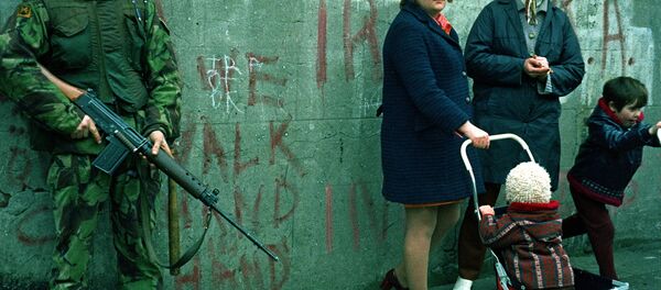 Women and children stand near an armed British military soldier patrols a street in Belfast, Northern Ireland, Feb. 1972. British paratroopers shot 13 demonstrators during a civil rights march on Jan. 30, known as Bloody Sunday. Women and children stand near an armed British military soldier patrols a street in Belfast, Northern Ireland, Feb. 1972. British paratroopers shot 13 demonstrators during a civil rights march on Jan. 30, known as Bloody Sunday. - Sputnik International