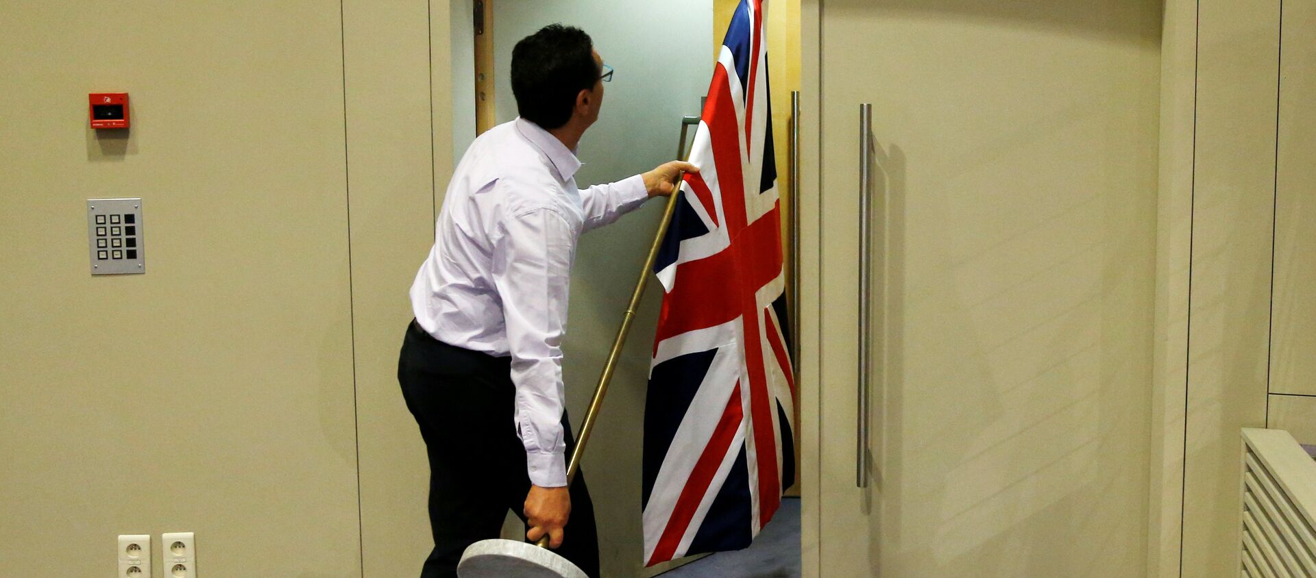 An official carries a Union Jack flag ahead of a news conference by Britain's Secretary of State for Exiting the European Union David Davis and European Union's chief Brexit negotiator Michel Barnier in Brussels, Belgium July 20, 2017 - Sputnik International, 1920, 06.03.2021