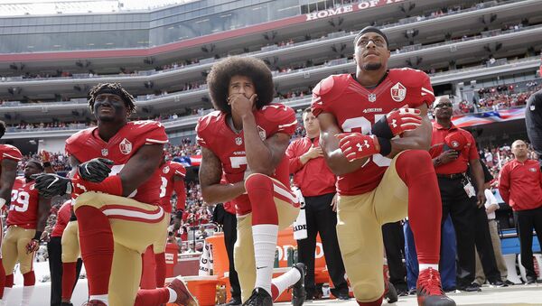 FILE - In this Oct. 2, 2016 file photo, from left, San Francisco 49ers outside linebacker Eli Harold, quarterback Colin Kaepernick and safety Eric Reid kneel during the national anthem before an NFL football game against the Dallas Cowboys in Santa Clara, Calif. In recent months, Colin Kaepernick has become comfortable with people knowing him as more than a laser-focused football player as he always previously preferred it. Perhaps, through the anthem protest and his emergence as an outspoken activist for minorities, Kaepernick has improved his image in the process. - Sputnik International