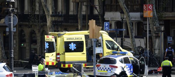 A policemen and a medical staff member stand past police cars and an ambulance in a cordoned off area after a van ploughed into the crowd, injuring several persons on the Rambla in Barcelona on August 17, 2017 - Sputnik International