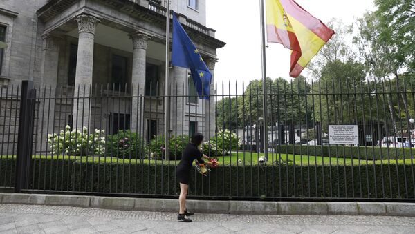 The Spanish and the European flag fly at half mast as a woman fixes flowers at the fence of the Spanish embassy in Berlin, on August 18, 2017 in tribute to victims of the Barcelona attack - Sputnik International