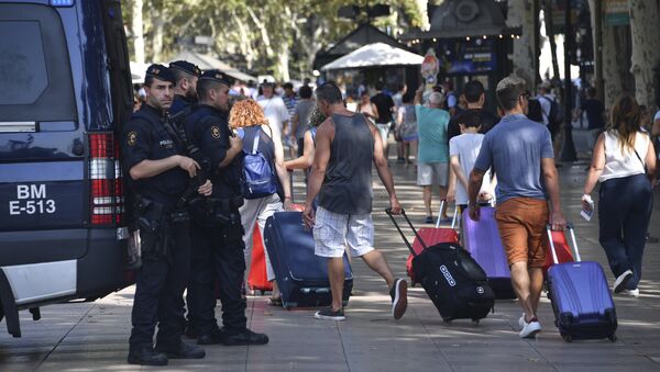 Spanish policemen stand guard as tourists pass by with their suitcases on the Rambla boulevard on August 18, 2017 - Sputnik International