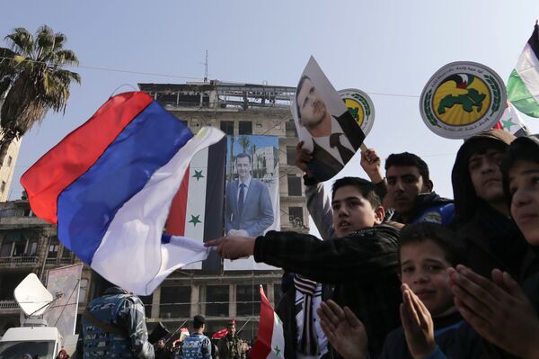 Pro-government supporters wave the Russian national flag and pictures of Syrian President Bashar Assad, as gathering at the Saadallah al-Jabiri Square in Aleppo, Syria, Thursday, Jan. 19, 2017 - Sputnik International