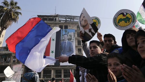 Pro-government supporters wave the Russian national flag and pictures of Syrian President Bashar Assad, as gathering at the Saadallah al-Jabiri Square in Aleppo, Syria, Thursday, Jan. 19, 2017 - Sputnik International