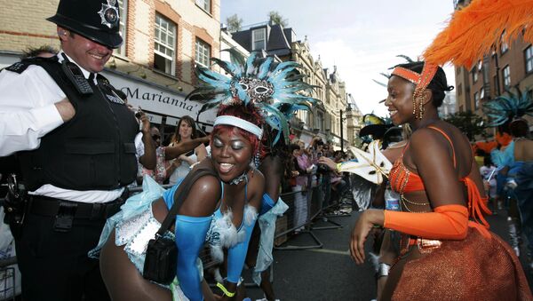 Participants in costumes dance in front of a British police officer during the Notting Hill Carnival in London, Monday Aug. 27, 2007. - Sputnik International