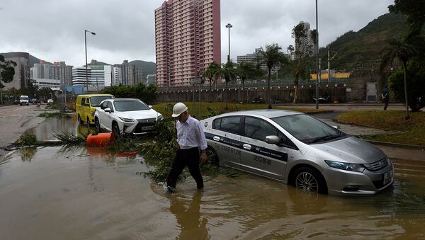 A man wades through floodwaters away from his car after heavy rains brought on by Typhoon Hato in Hong Kong on August 23, 2017 - Sputnik International