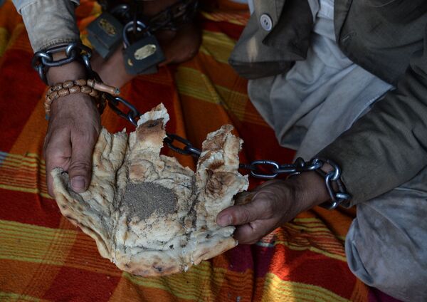 In this photograph taken on May 2, 2017, a mentally ill Afghan patient has his lunch of bread and black pepper as he sits chained to a wall at the Mia Ali Baba holy shrine in the village of Samar Khel on the outskirts of Jalalabad - Sputnik International