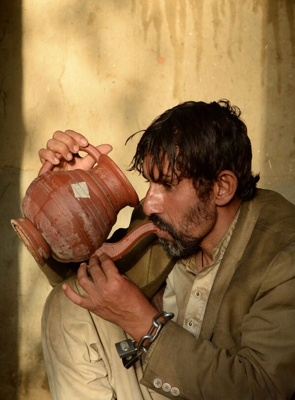 In this photograph taken on May 7, 2017, a mentally ill Afghan patient drinks water as he sits chained to a wall at the Mia Ali Baba holy shrine in the village of Samar Khel on the outskirts of Jalalabad - Sputnik International