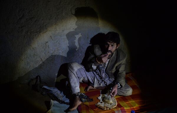 In this photograph taken on May 7, 2017, a mentally ill Afghan patient eats bread as he sits chained to a wall at the Mia Ali Baba holy shrine in the village of Samar Khel on the outskirts of Jalalabad - Sputnik International
