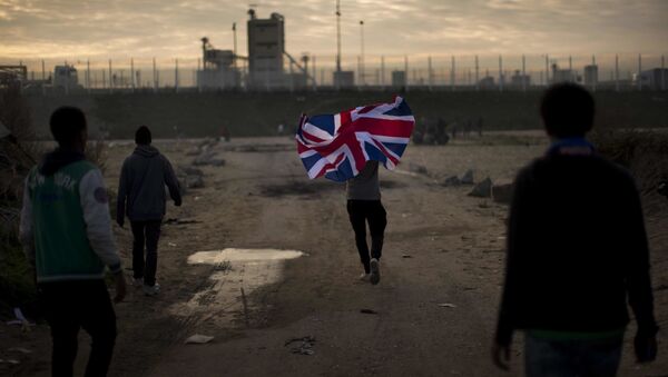 In this Tuesday, Oct. 25, 2016 file photo a man runs with a British flag inside a makeshift camp known as the jungle near Calais, northern France. - Sputnik International