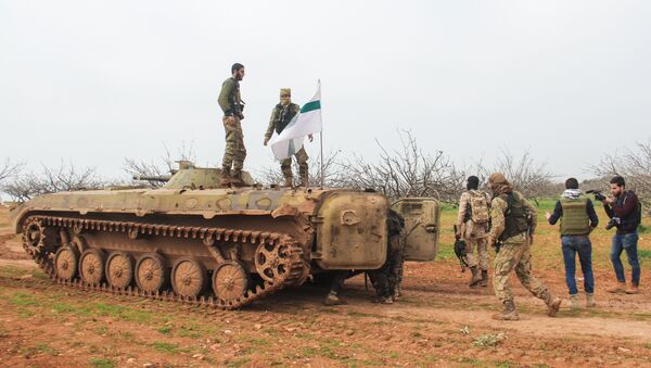 A picture taken on March 22, 2017 near the town of Maardes in the countryside of the central Syrian province of Hama, shows rebel fighters walking past an armoured vehicle carrying the flag of the Tahrir al-Sham rebel alliance - Sputnik International