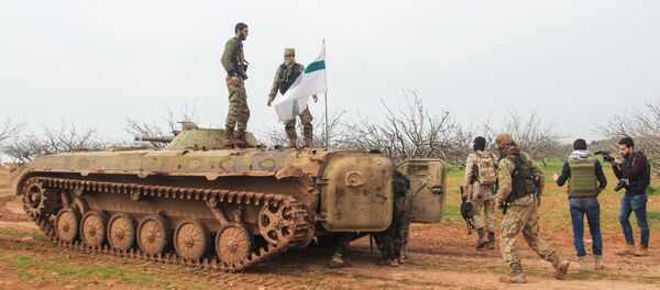 A picture taken on March 22, 2017 near the town of Maardes in the countryside of the central Syrian province of Hama, shows rebel fighters walking past an armoured vehicle carrying the flag of the Tahrir al-Sham rebel alliance - Sputnik International