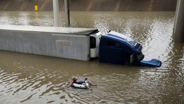 A man floats past a truck submerged on a freeway flooded by Tropical Storm Harvey on Sunday, Aug. 27, 2017, near downtown Houston. - Sputnik International