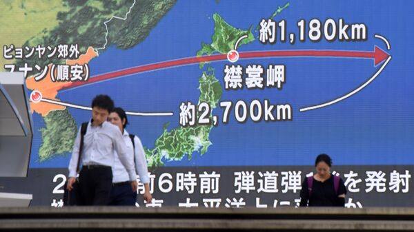 Pedestrians walk in front of a huge screen displaying a map of Japan (R) and the Korean Peninsula, in Tokyo on August 29, 2017, following a North Korean missile test that passed over Japan. - Sputnik International