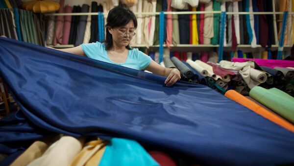 A vendor prepares rolls of silk at her textile and fabric shop in Beijing - Sputnik International