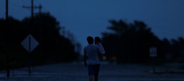 Ethan holds his 2-year-old daughter Zella as they walk through flood waters from Tropical Storm Harvey in Iowa, Calcasieu Parish, Louisiana, U.S - Sputnik International