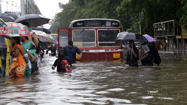 People walk through a waterlogged street following heavy rains in Mumbai, India - Sputnik International