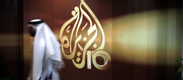 A Qatari employee of Al Jazeera Arabic language TV news channel passes by the logo of Al Jazeera in Doha, Qatar. (File) A Qatari employee of Al Jazeera Arabic language TV news channel passes by the logo of Al Jazeera in Doha, Qatar. (File) - Sputnik International