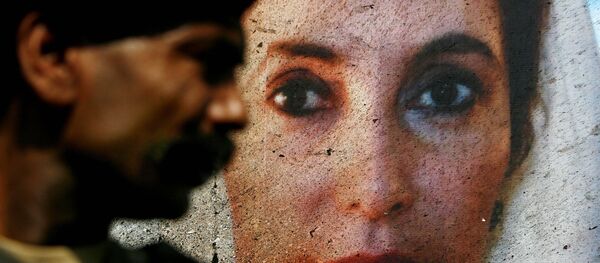 A portrait of Benazir Bhutto on the side of her open-air vehicle is splattered with bomb residue, as it is guarded by a Pakistani soldier in Karachi, Pakistan, on Friday Oct. 19, 2007, following an assassination attempt on Thursday. A portrait of Benazir Bhutto on the side of her open-air vehicle is splattered with bomb residue, as it is guarded by a Pakistani soldier in Karachi, Pakistan, on Friday Oct. 19, 2007, following an assassination attempt on Thursday. - Sputnik International