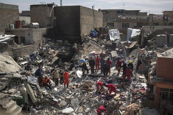 In this Friday, March 24, 2017 photo, civil protection rescue teams work on the debris of a destroyed house to recover bodies of people killed during fighting between Iraqi security forces and Daesh militants on the western side of Mosul, Iraq - Sputnik International