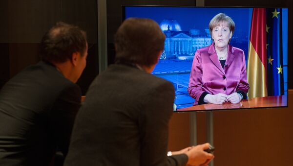 Employees of the chancellery and tv crew watch on a screen as German Chancellor Angela Merkel records her annual New Year's speech at the Chancellery in Berlin on December 30, 2014 - Sputnik International