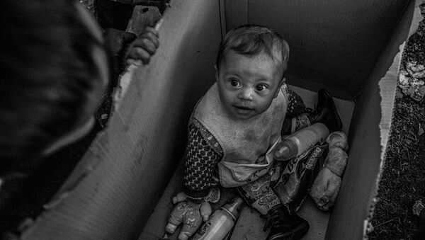 A baby sits in a cardboard box in the Idomeni camp on the Greek-Macedonian border - Sputnik International