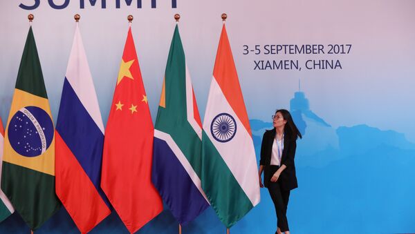 A staff worker walks past the national flags of Brazil, Russia, China, South Africa and India before a group photo during the BRICS Summit at the Xiamen International Conference and Exhibition Center in Xiamen, southeastern China's Fujian Province, China September 4, 2017 - Sputnik International
