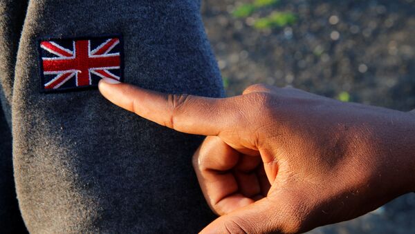 An Ethiopian migrant named Ermias (16 years old) points at an Union Jack patch as he waits on line during a food distribution near the former jungle in Calais, France, August 23, 2017 - Sputnik International