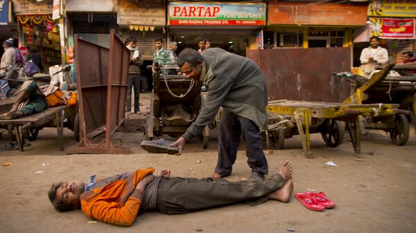 In this Friday, Dec. 12, 2014 photo, a drunk man offers his shoes to his colleague who passed out after consuming alcohol in New Delhi, India - Sputnik International