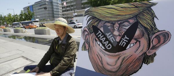 A South Korean protester sits next to a poster with an illustration of U.S. President Donald Trump to oppose a plan to deploy an advanced U.S. missile defense system called Terminal High-Altitude Area Defense, or THAAD, near the U.S. Embassy in Seoul Monday, June 5, 2017 A South Korean protester sits next to a poster with an illustration of U.S. President Donald Trump to oppose a plan to deploy an advanced U.S. missile defense system called Terminal High-Altitude Area Defense, or THAAD, near the U.S. Embassy in Seoul Monday, June 5, 2017 - Sputnik International