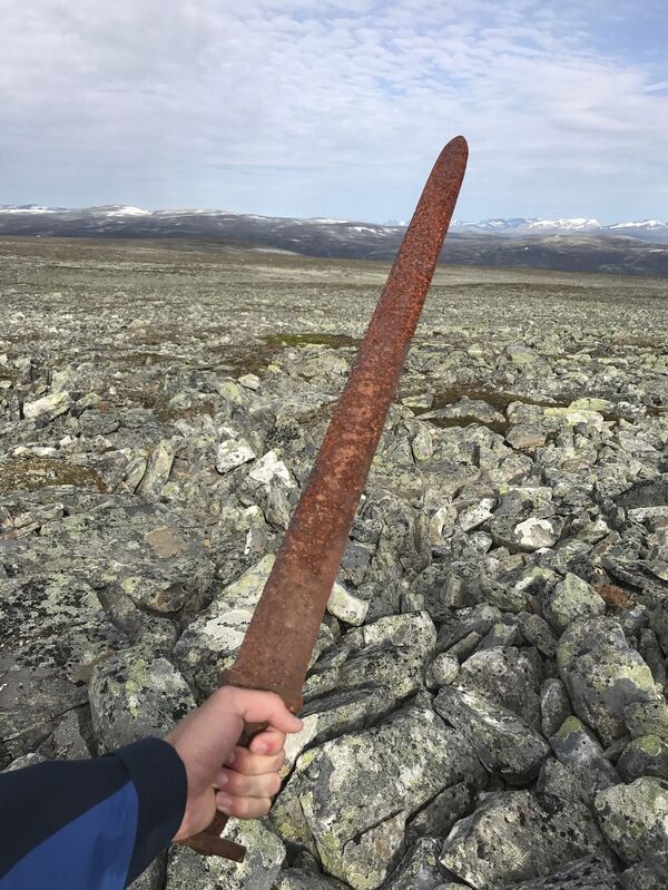 In this photo taken on Aug. 23, 2017, Einar Ambakk, one of the hunters that found an ancient Viking sword slid down between rocks during a reindeer hunt, raises it in Lesja, some 275 kilometers (170 miles) north of Oslo. According to a Norwegian archeologist, the nearly 1-meter-long (3-foot) sword dating from about 850-950 A.D. may have been left by a person who got lost in a blizzard and died on the mountain from exposure. In this photo taken on Aug. 23, 2017, Einar Ambakk, one of the hunters that found an ancient Viking sword slid down between rocks during a reindeer hunt, raises it in Lesja, some 275 kilometers (170 miles) north of Oslo. According to a Norwegian archeologist, the nearly 1-meter-long (3-foot) sword dating from about 850-950 A.D. may have been left by a person who got lost in a blizzard and died on the mountain from exposure. - Sputnik International