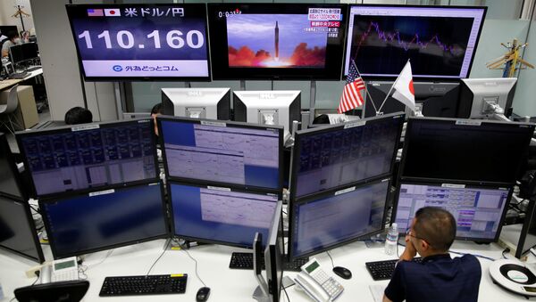 An employee of a foreign exchange trading company works in front of monitors showing TV news on North Korea's missile launch (top C) and the Japanese yen's exchange rate against the U.S. dollar (top L) in Tokyo, Japan, September 15, 2017 - Sputnik International