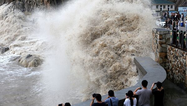 People stand beside a big wave on a waterfront as Typhoon Talim approaches in Wenling, Zhejiang province, China September 14, 2017 - Sputnik International