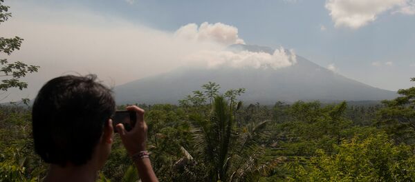 A local resident takes a picture of Mount Agung, an active volcano that authorities say is showing increased activity, from a monitoring station in Rendang Village, Karangasem on the resort island of Bali, Indonesia September 19, 2017 - Sputnik International