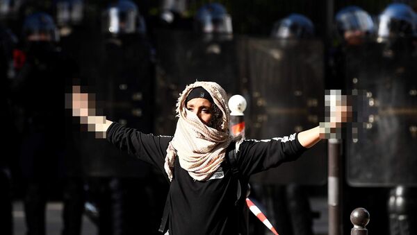A demonstrator sticks up her middle fingers next to riot police during a rally in Paris on September 21, 2017, against the French government's proposed labour law reforms - Sputnik International