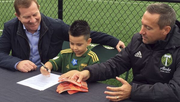 Five-year-old Derrick Tellez, center, signs his contract with Portland Timbers general manager Gavin Wilkinson, left, and coach Caleb Porter, right, on Friday, Sept. 22, 2017, at the Timbers’ practice facility in Beaverton, Ore. - Sputnik International